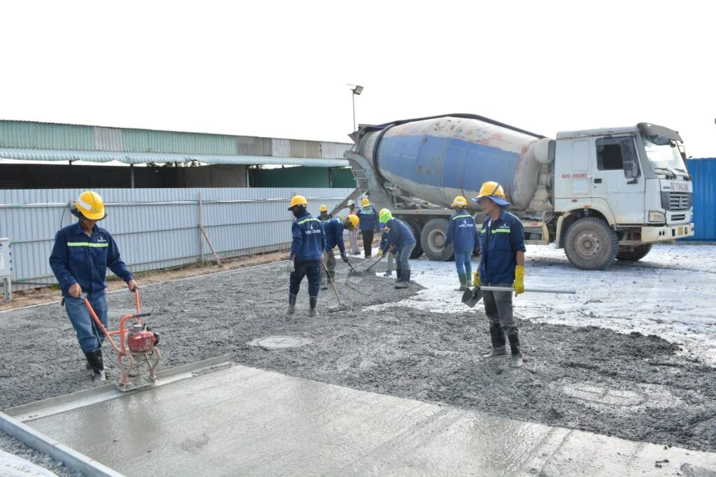 Crew placing and leveling concrete from a mixer truck on a job site