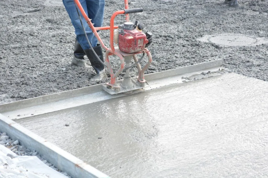 Worker guiding a power trowel across freshly poured concrete