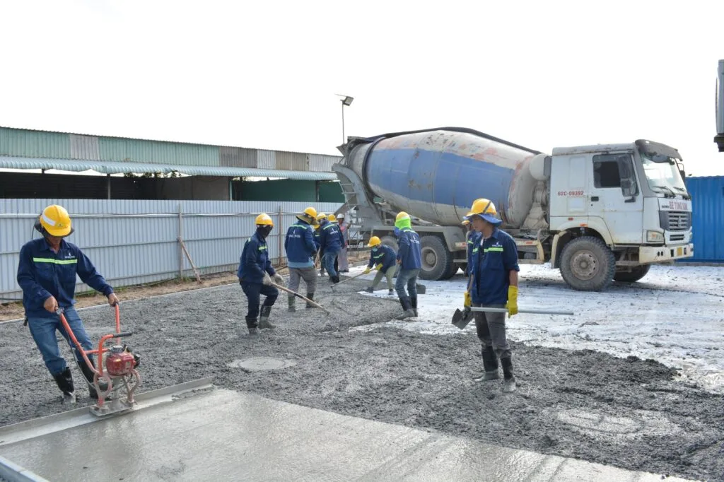 Concrete crew in safety gear pouring a slab from a mixer truck