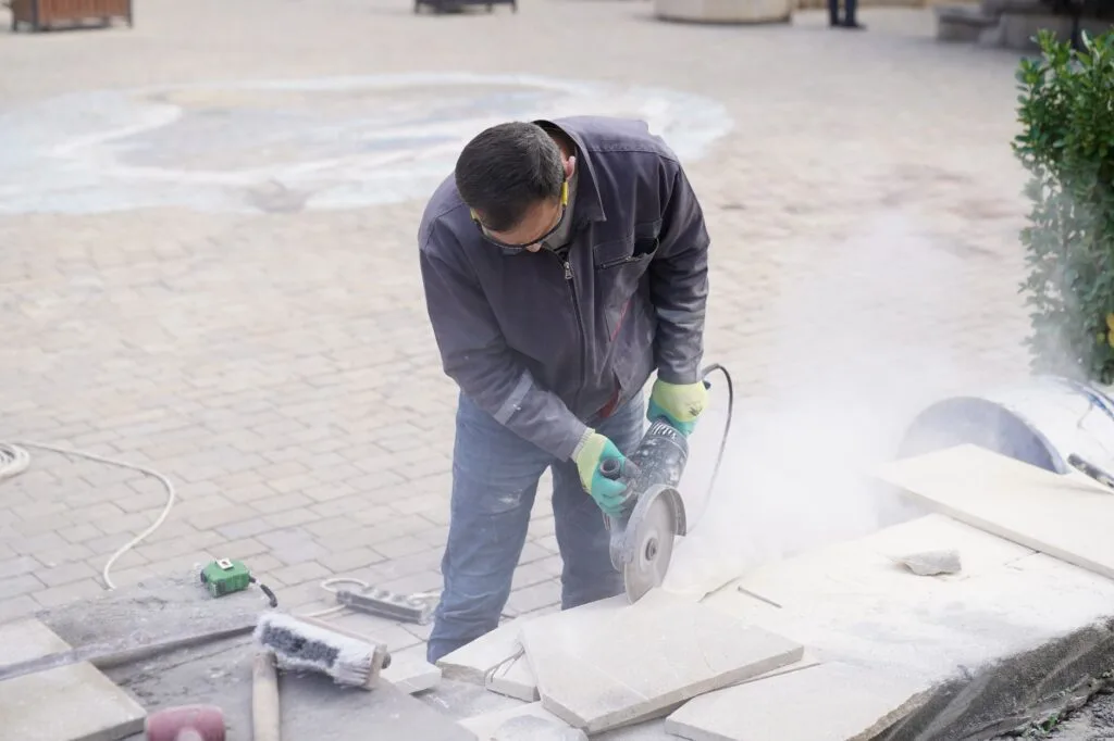 Worker making a cut with a handheld power saw, the tool used for control joints
